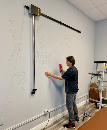 Commercial mural drawing robot Botsy installed on the wall.  This artistic robotic tool scales up and transfers images, pictures on a wall. This drawing machine outlines fast, precisely and saves time. There is no need for carbon transfer, punched paper.